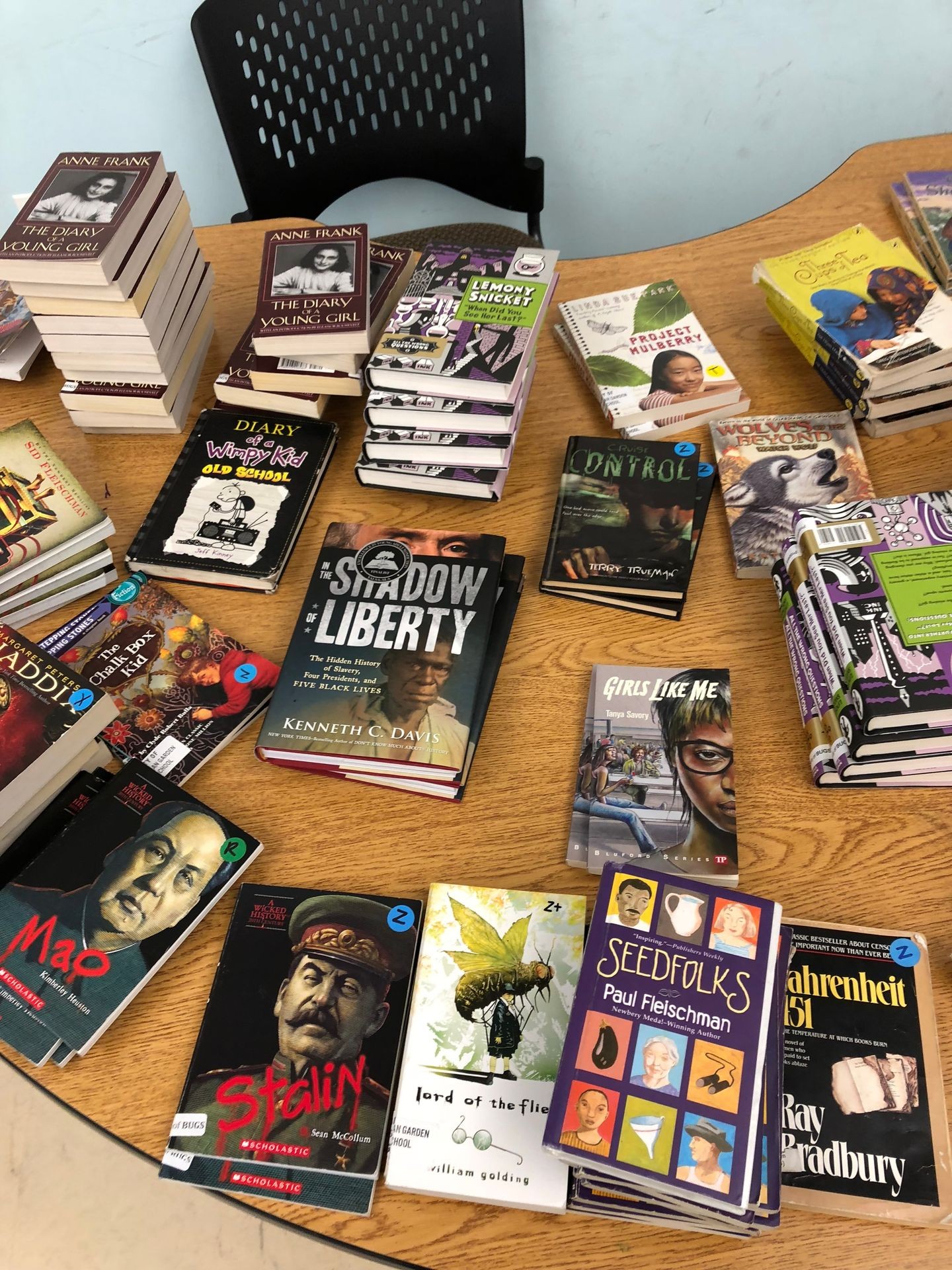 Assorted books displayed on a wooden table, including titles by Anne Frank and Ray Bradbury.